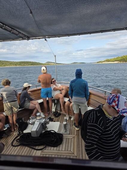 A group of people on a boat with a fishing rod, a person in a blue jacket, and a Croatian flag. 3