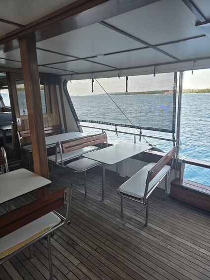 A boat deck with tables and benches, a railing, and a view of the water. 2