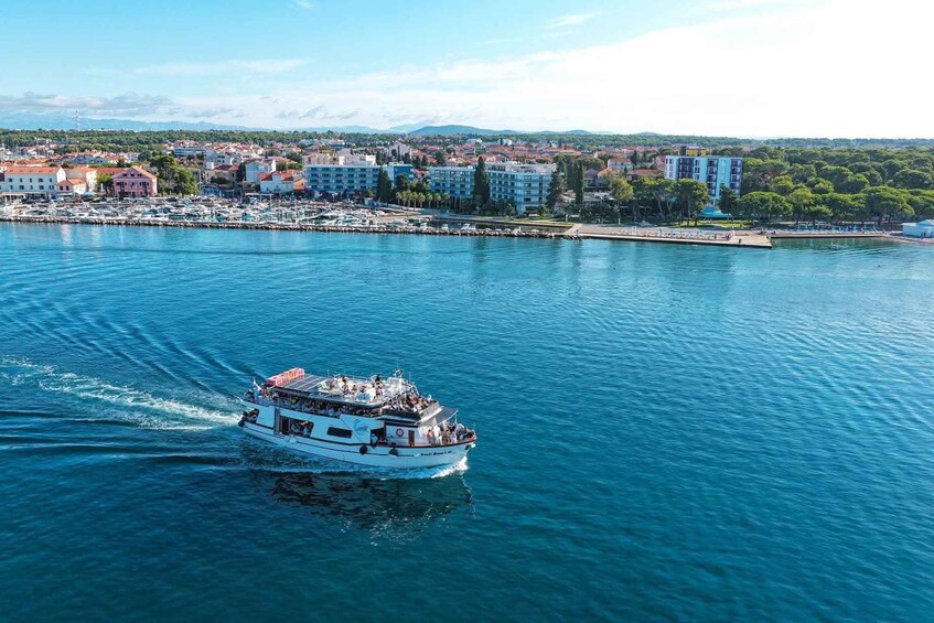 A boat on a calm body of water with a marina and buildings in the background. 4