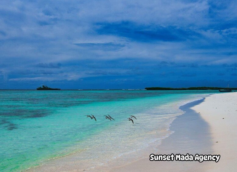 A beach with clear turquoise water, a sandy shore, and a distant island. 1
