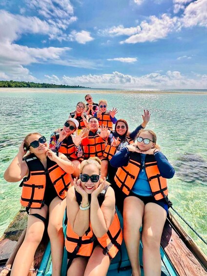 A group of people on a boat wearing life jackets, with a clear blue sky and calm water. 4