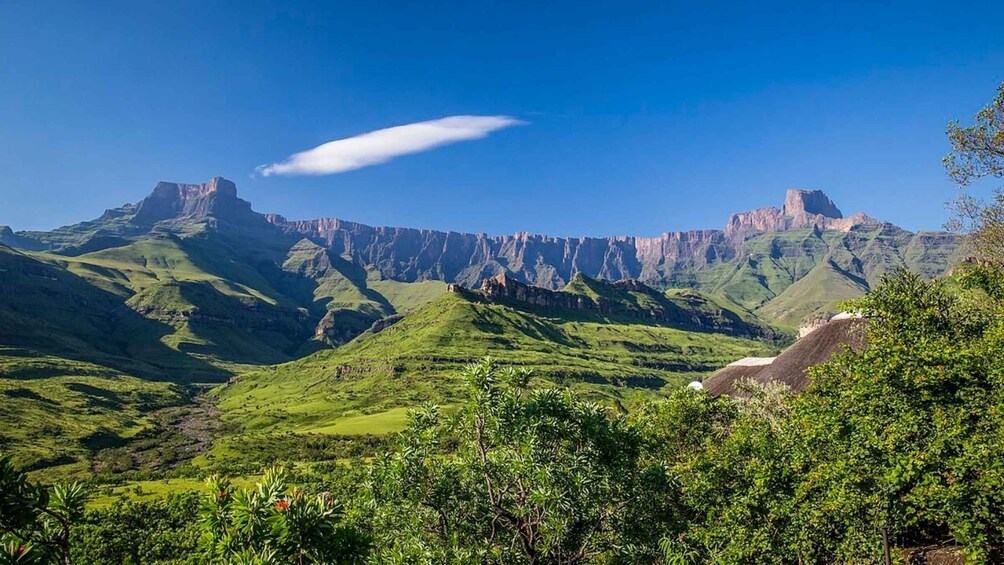 A mountainous landscape with green valleys and rocky cliffs under a clear blue sky. 3