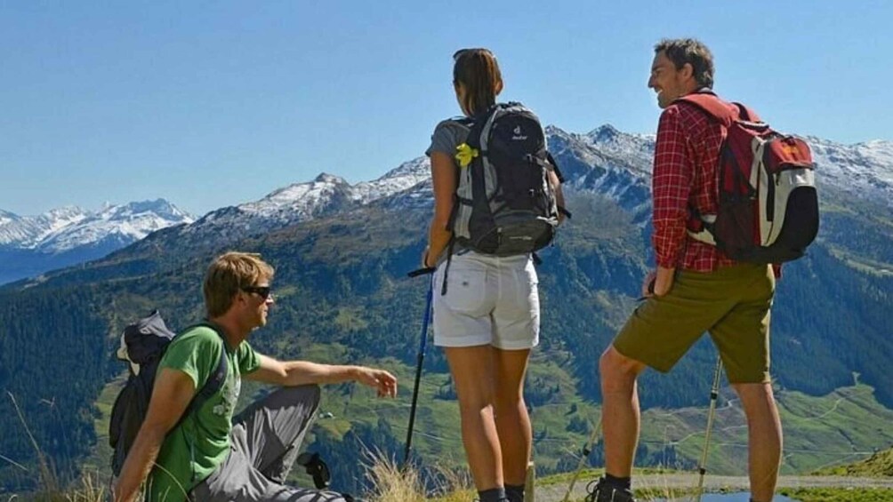 Three hikers on a mountain trail with snow-capped peaks in the background. 4