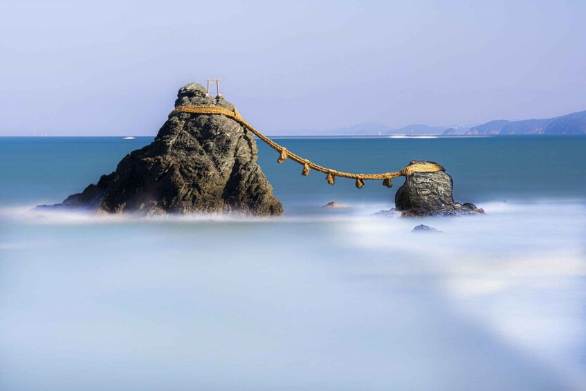 A rope bridge over a rocky sea with a lighthouse in the background. 4