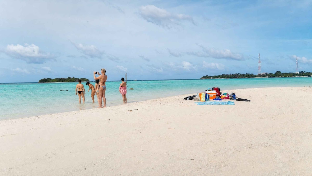 A beach with people in swimwear, a sandy shore, and a small island in the distance. 5