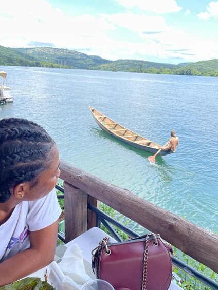 A person rowing a canoe on a calm lake with hills in the background. 3