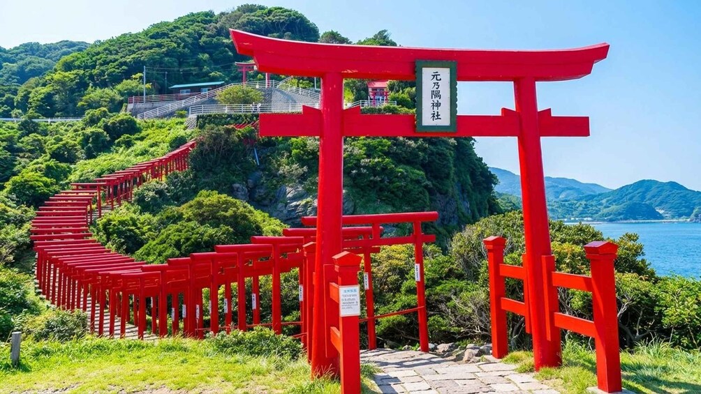 A red torii gate leading to a shrine surrounded by lush greenery and a mountainous backdrop. 2