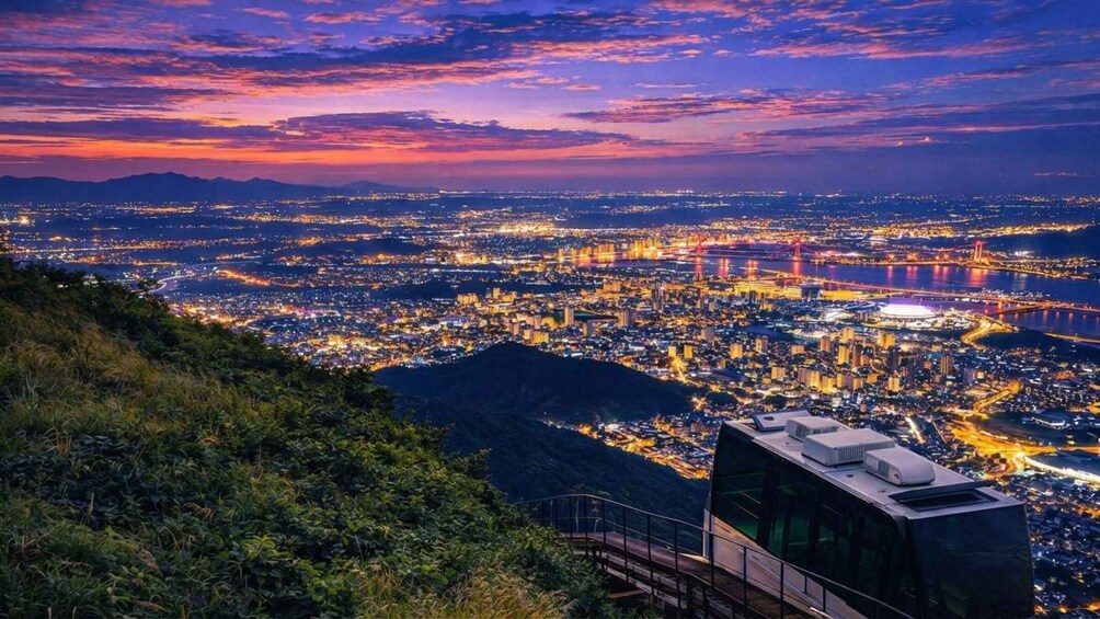 A cityscape at dusk with a view of a bridge and a mountain in the foreground. 1