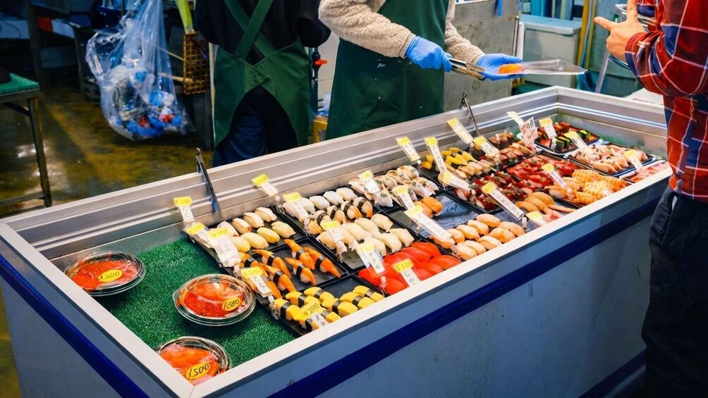 A sushi display with various types of sushi and pickled vegetables. 5