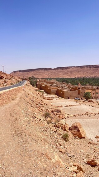 A desert landscape with a winding road, traditional mud-brick buildings, and sparse vegetation. 3