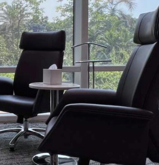 A modern office chair with a high backrest and armrests, positioned next to a small round table with a tissue box on it. 5