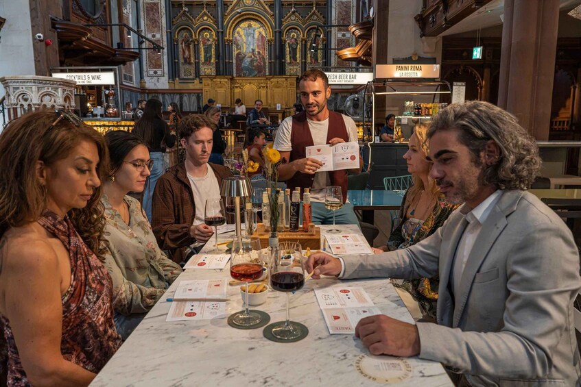 A group of people at a wine tasting event in a historic building with ornate decorations. 5