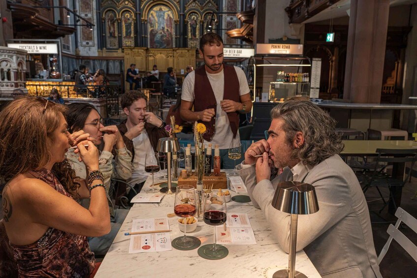 A group of people tasting wine at a table with wine glasses, bottles, and tasting notes. 3