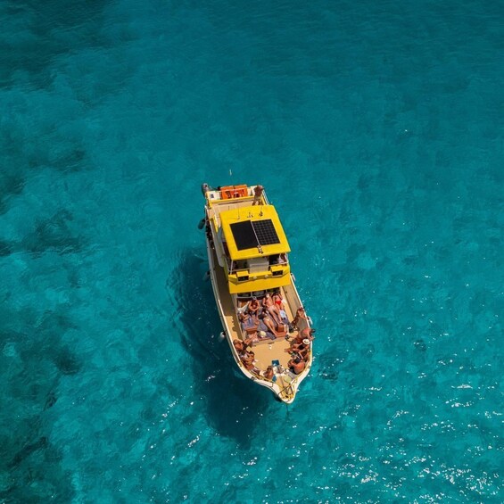A yellow boat with passengers on a clear turquoise sea. 3