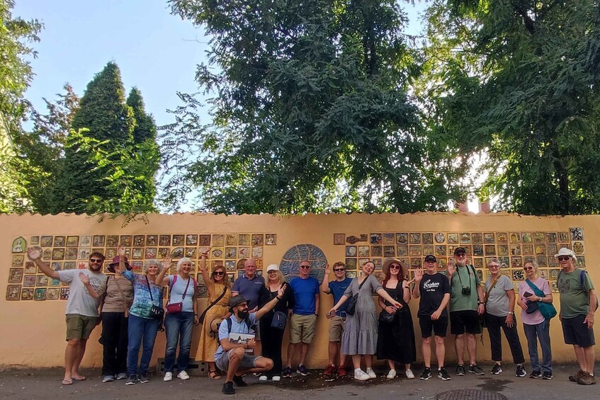 A group of people standing in front of a wall with various framed pictures. 1