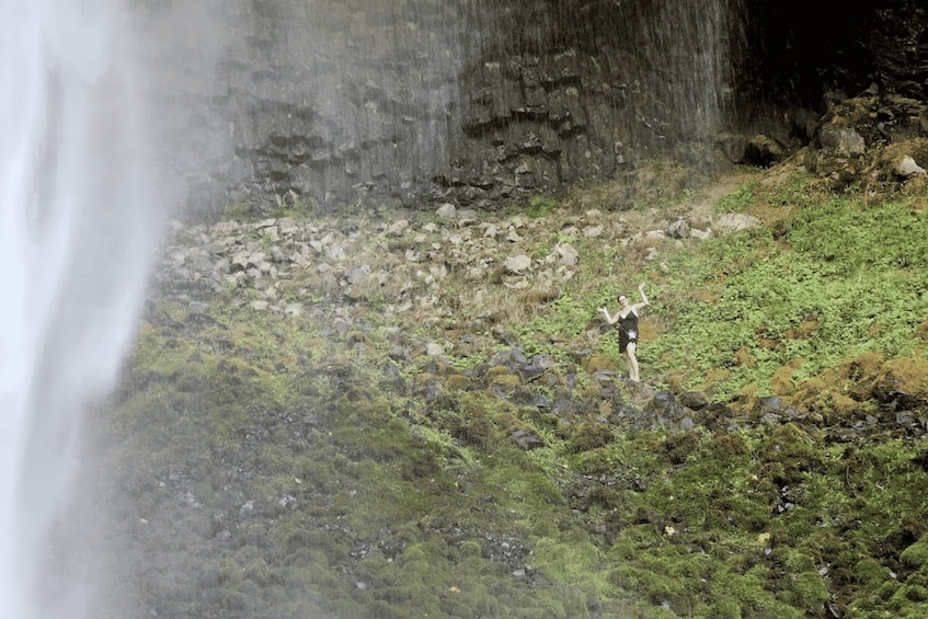 A waterfall, rocky terrain, and a person standing on a grassy area. 3