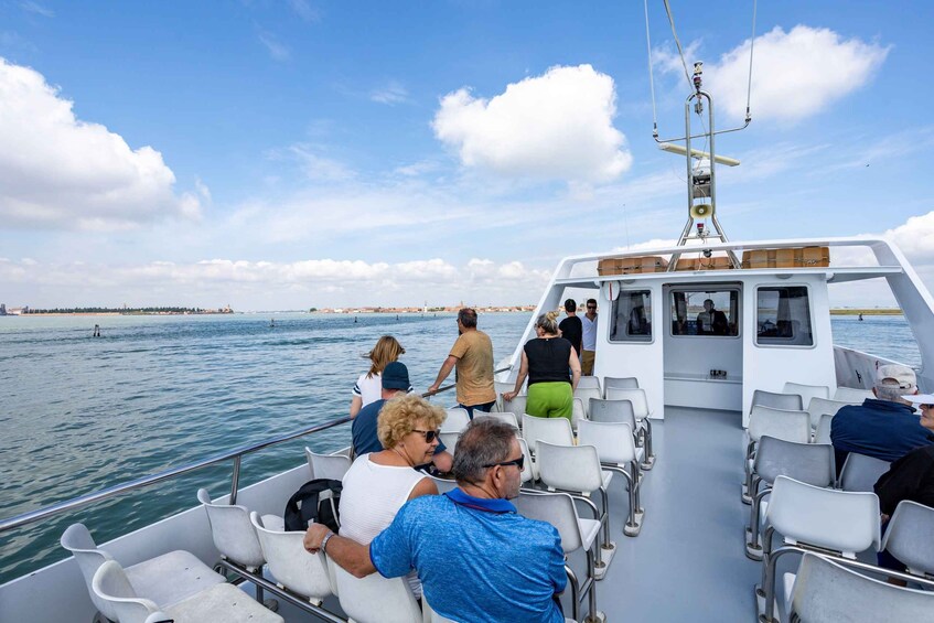 A boat with people on board, a clear sky, and a distant shoreline. 4
