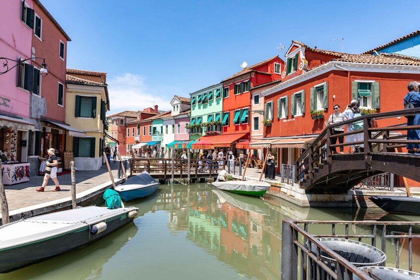 A canal with colorful buildings, a wooden bridge, and boats. 3
