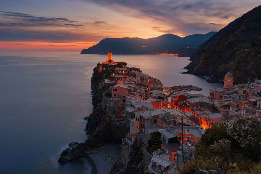 A coastal town at sunset with buildings illuminated against the sky. 3