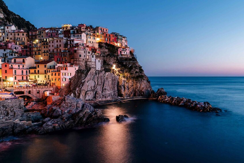 A coastal town at dusk with colorful buildings perched on a cliff overlooking the sea. 4