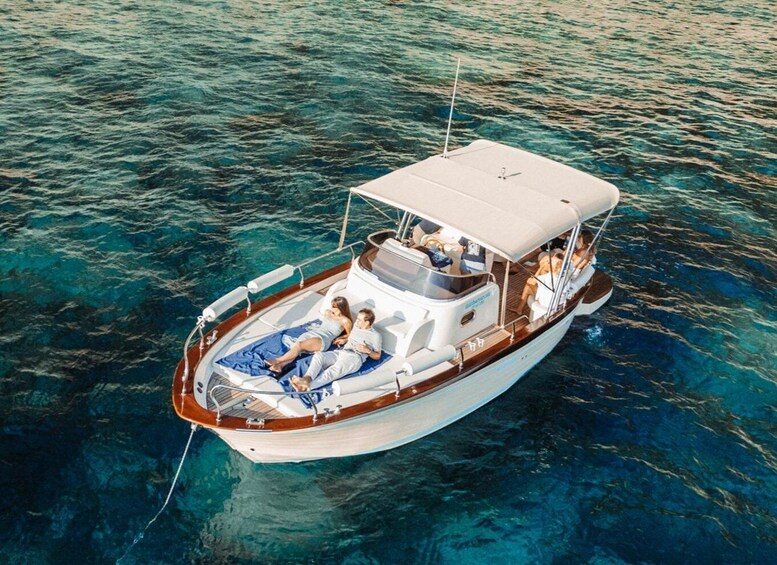 A boat with a covered deck and two people relaxing on a blue mat. 1