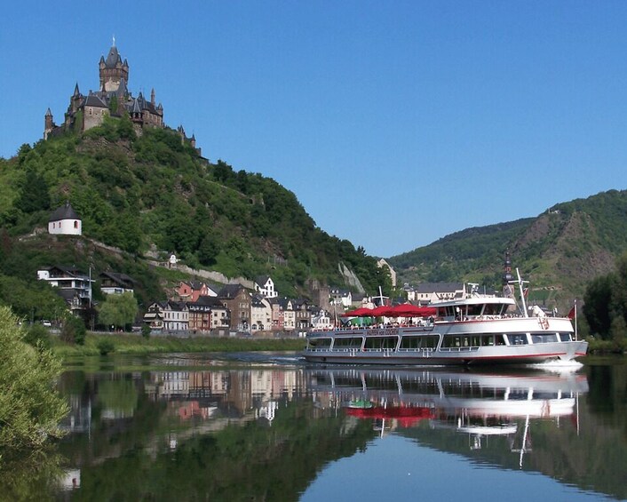 A river with a castle on a hill, a boat, and buildings along the riverbank. 3