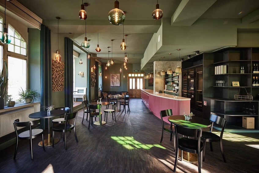 A modern interior with wooden floors, tables, chairs, and hanging pendant lights. 2