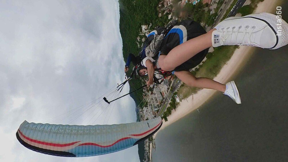 Une personne pratiquant le parapente au-dessus d’une zone côtière, avec une vue sur la ville en arrière-plan. 3