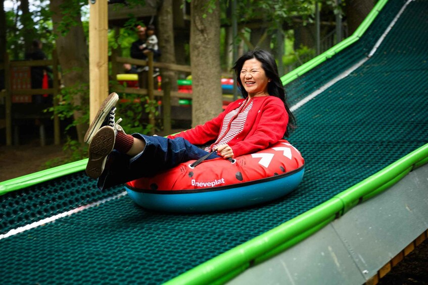 A person sliding down a green slide in a playground. 2