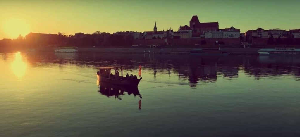 A calm river with a boat, buildings, and a church in the background during sunset. 4