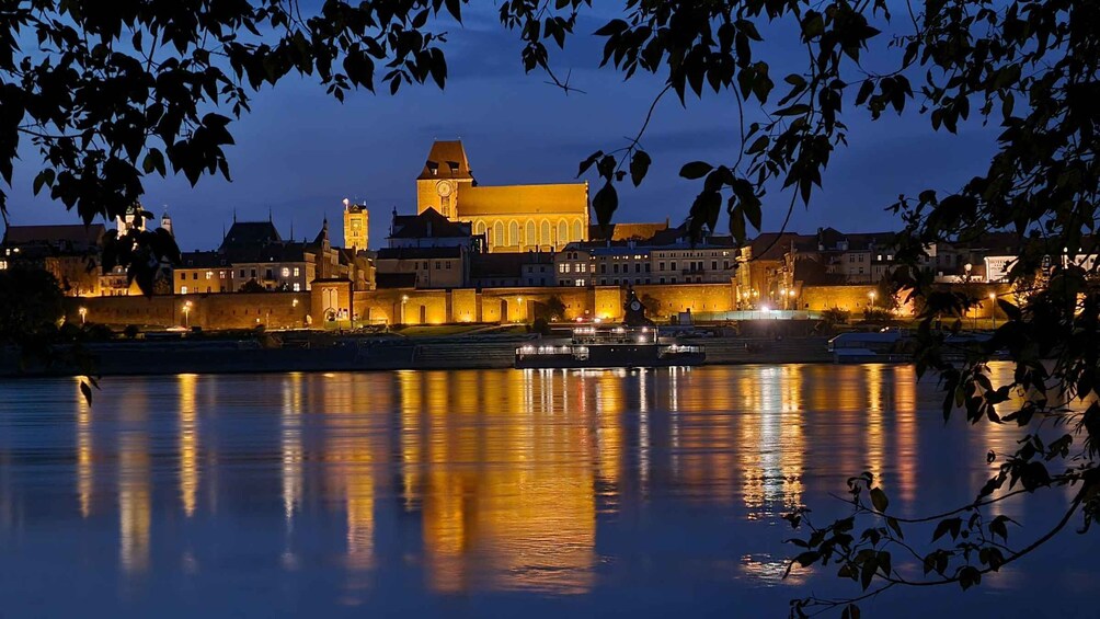 A cityscape at dusk with illuminated buildings reflecting on the water. 5