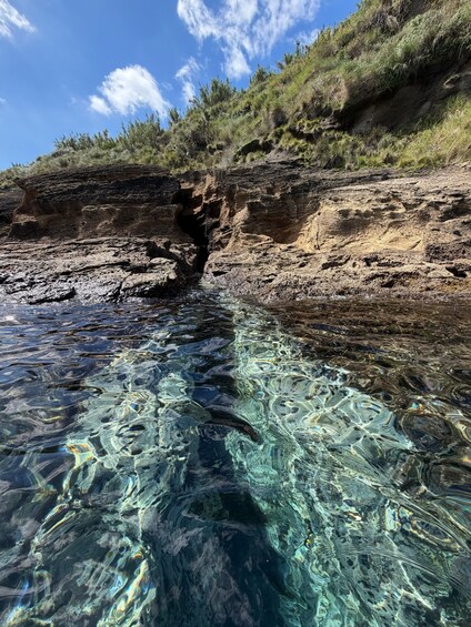 A clear coastal waterway with rocky cliffs and sparse vegetation. 4