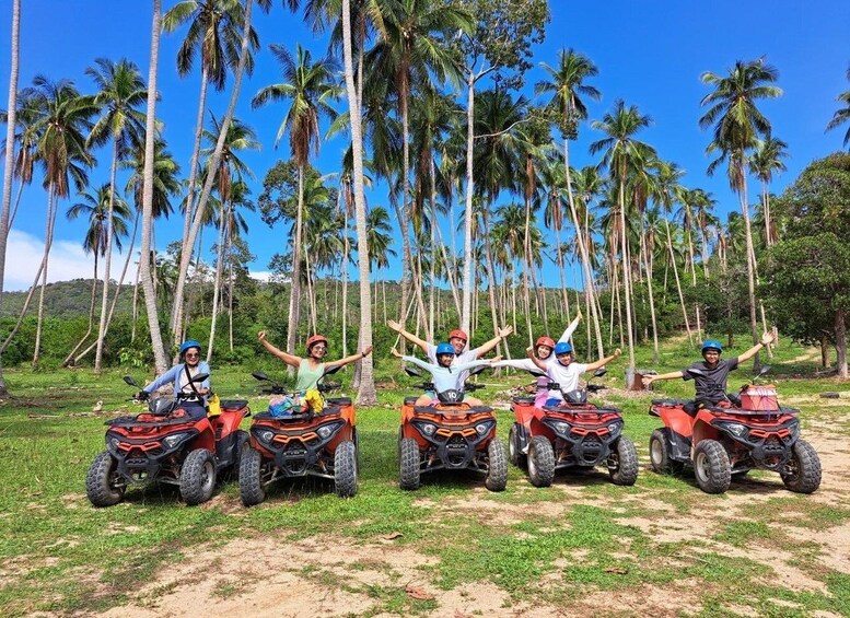 Four people on quad bikes with palm trees in the background. 5