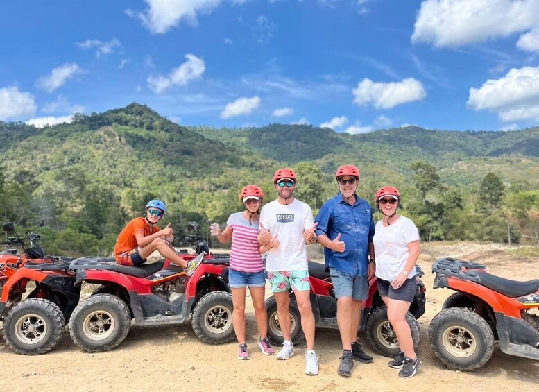 A group of people with quad bikes in a hilly outdoor setting. 1