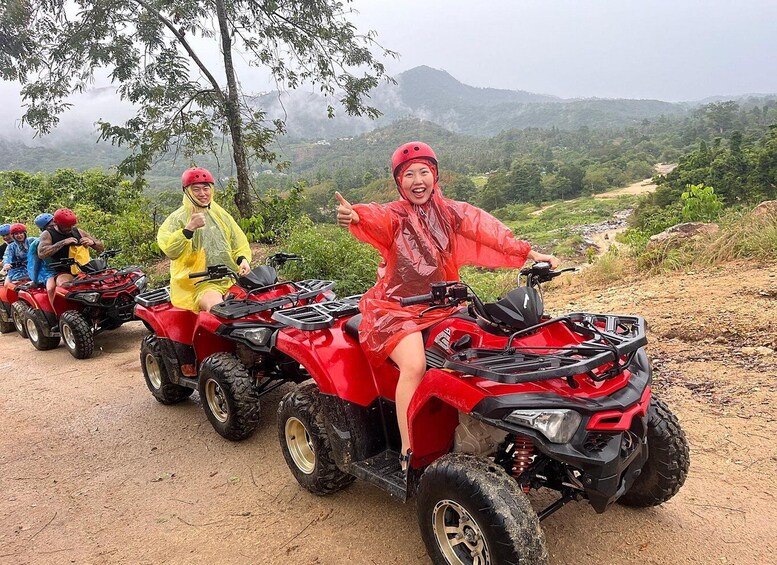 A group of people on red all-terrain vehicles on a dirt path with a mountainous landscape in the background. 2