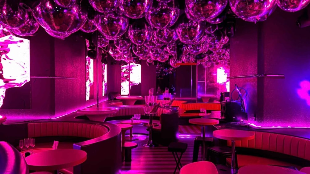 A bar with round tables and booths, illuminated by purple lighting. 2