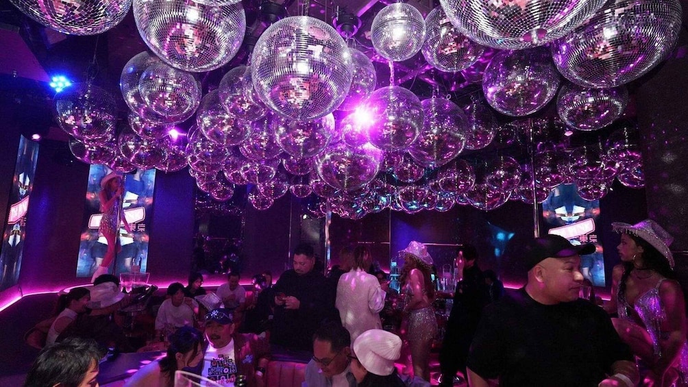 A crowded indoor venue with disco balls and people dancing. 1