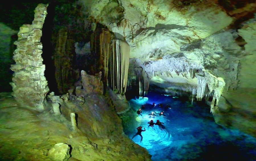 A cave with stalactites and stalagmites, and divers exploring the underwater passages. 1