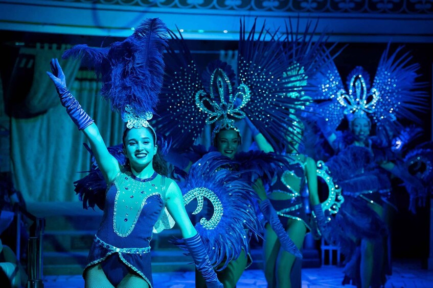 Performers in elaborate costumes with feathered headdresses and sparkling accessories. 3