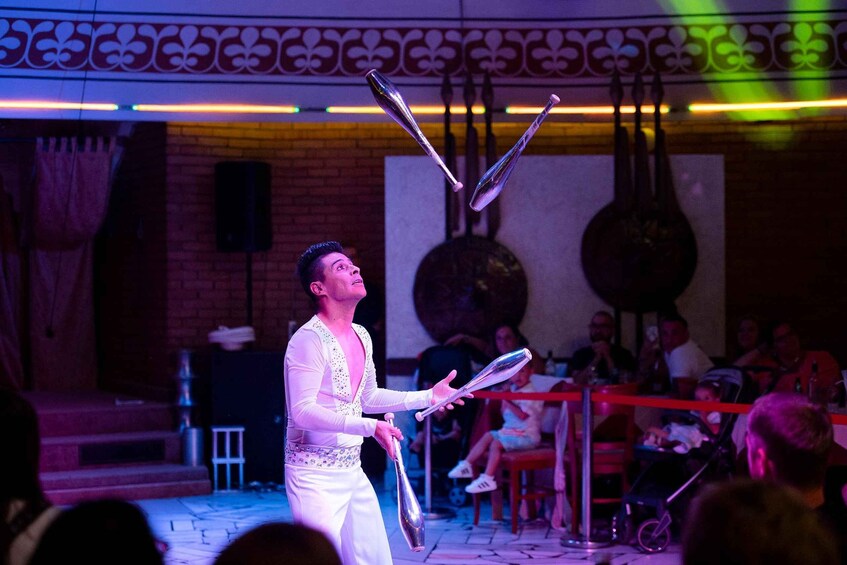 A performer juggling with metallic objects on a stage with an audience. 2