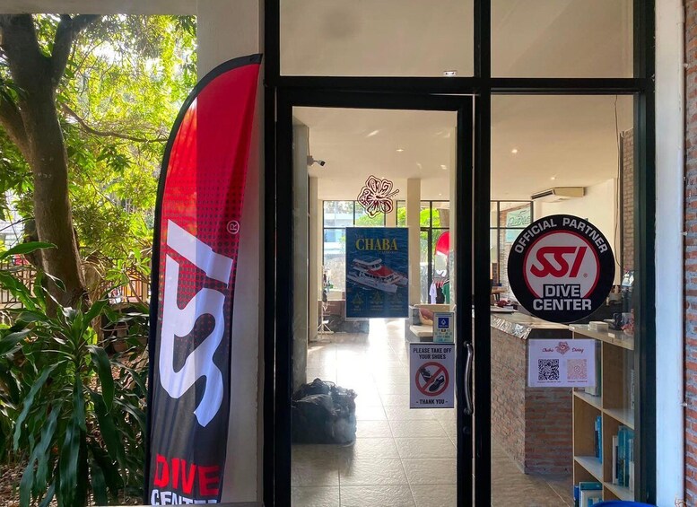 A dive center entrance with a large red and white sign, a logo, and a 'Please take off your shoes' sign. 2