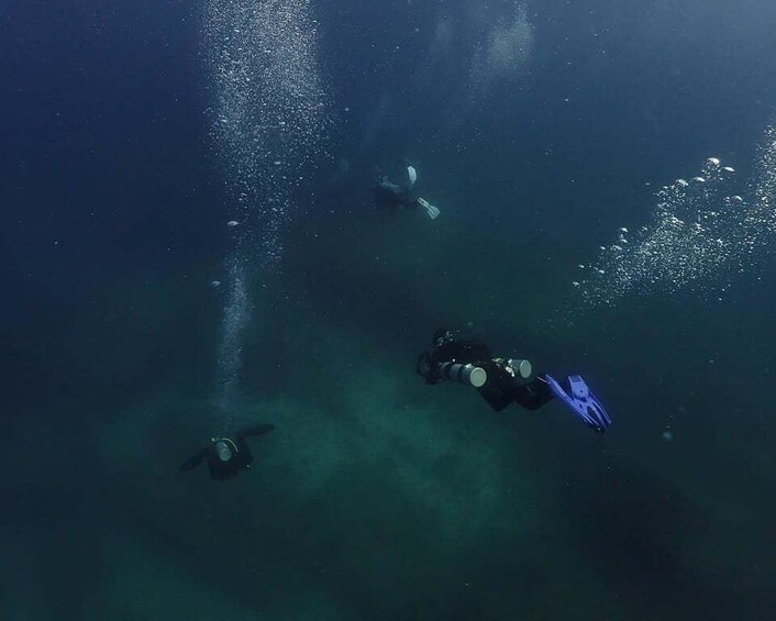 Three divers underwater with bubbles and light reflections. 4