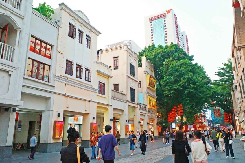 A bustling urban street lined with multi-story buildings, some with traditional architectural features. 1