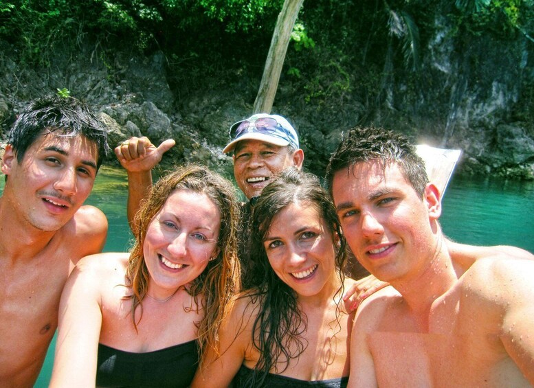 A group of people in a natural setting with a body of water and rocky cliffs in the background. 4