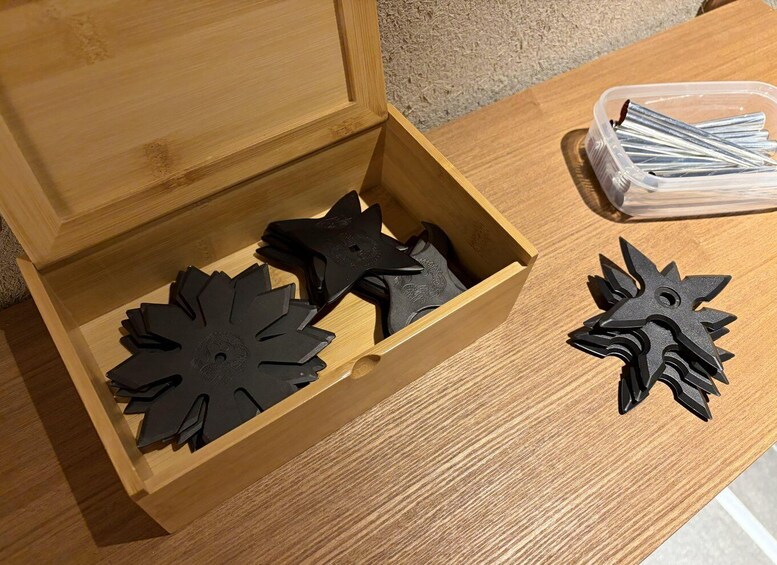 A wooden box with black star-shaped objects and a plastic container with metal rods. 4