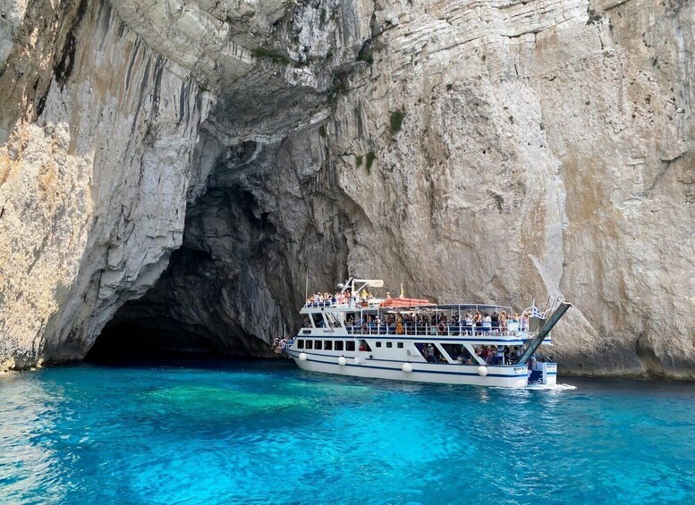 A boat with passengers near a rocky cave entrance. 1