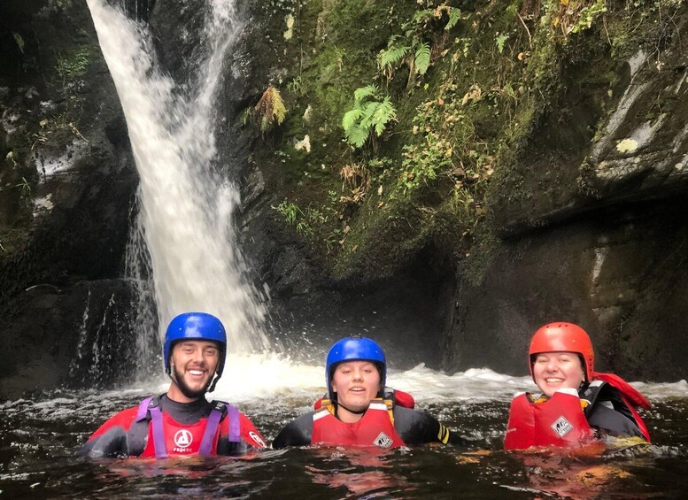 Three people kayaking in a river with a waterfall in the background. 3
