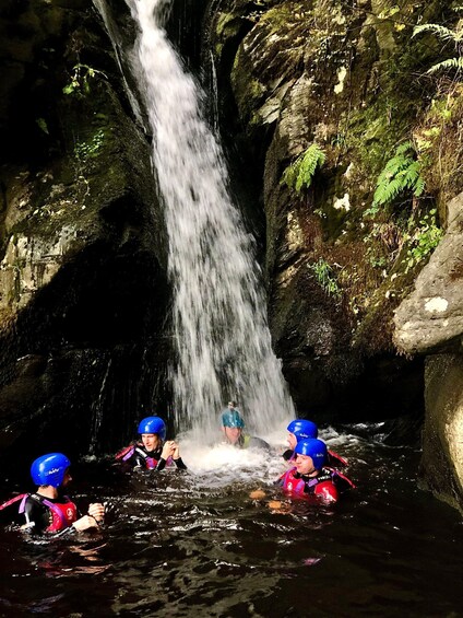 A waterfall in a rocky cave with people in water. 5