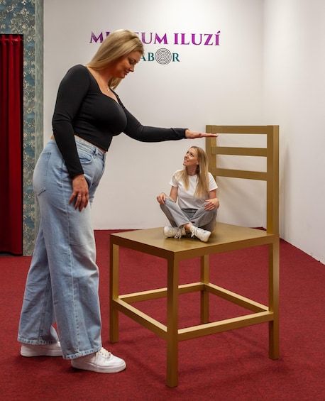 A woman standing next to a chair in a room with a red carpet and a wall with text. 4
