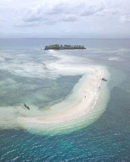 A white sandy beach with clear turquoise water, surrounded by a coral reef. 1